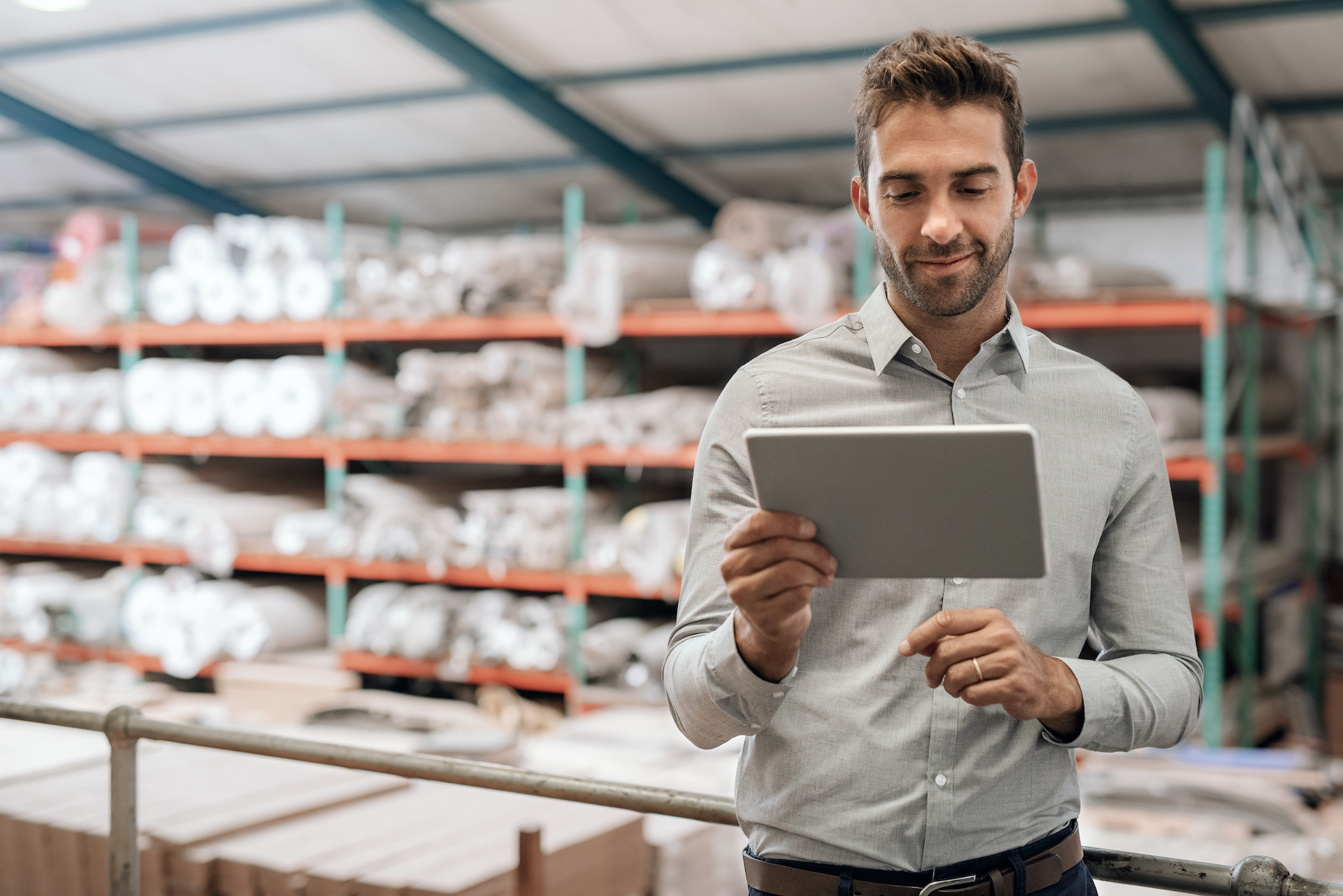 Happy distribution warehouse manager holding a cloud-enabled mobile tablet