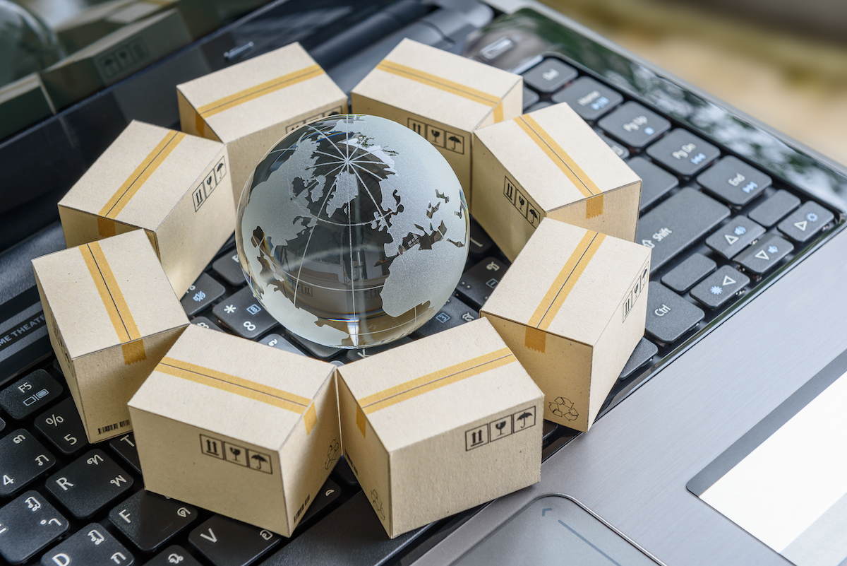 Supply Chain Challenges International freight or shipping service for online shopping or ecommerce concept : Paper boxes or carton put in circle around a clear crystal globe with world map on a computer notebook keyboard.